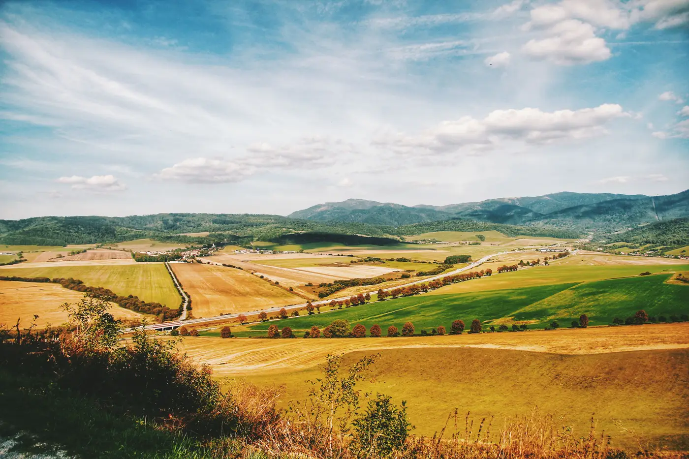 Patchwork of farm fields and hills under a clear blue sky.